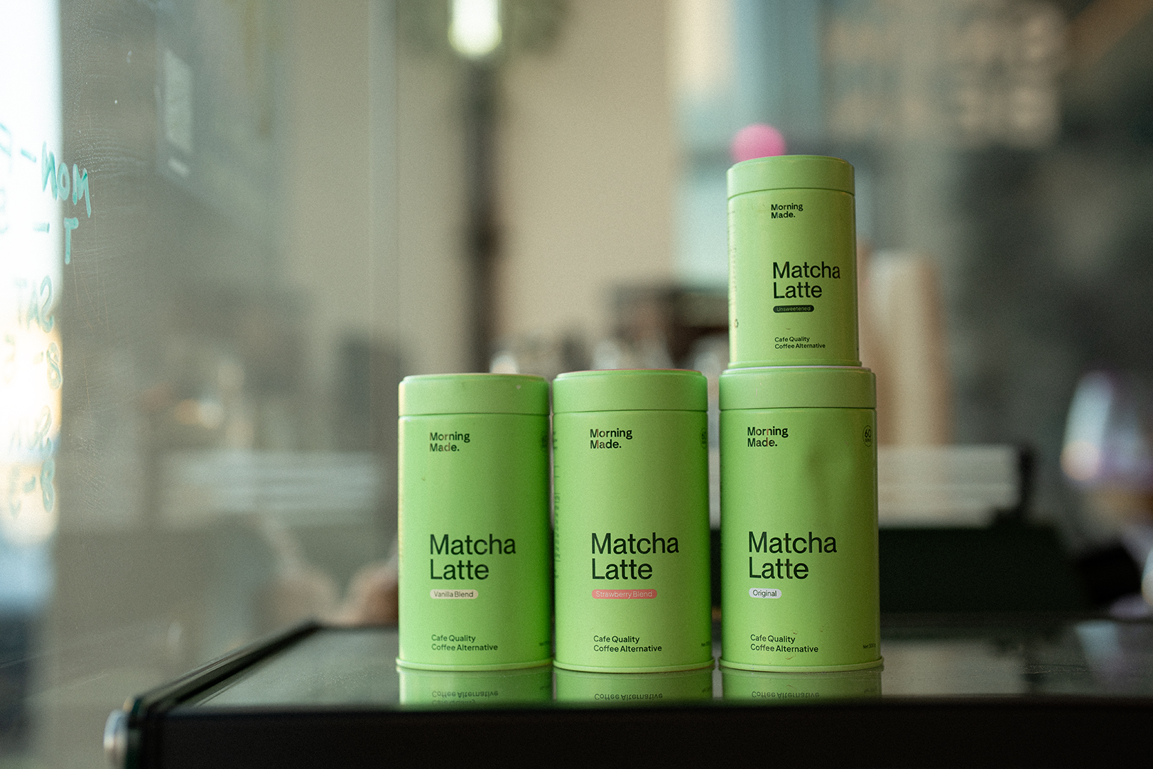 Tins of Snow Bean's matcha latte lined up on the counter.
