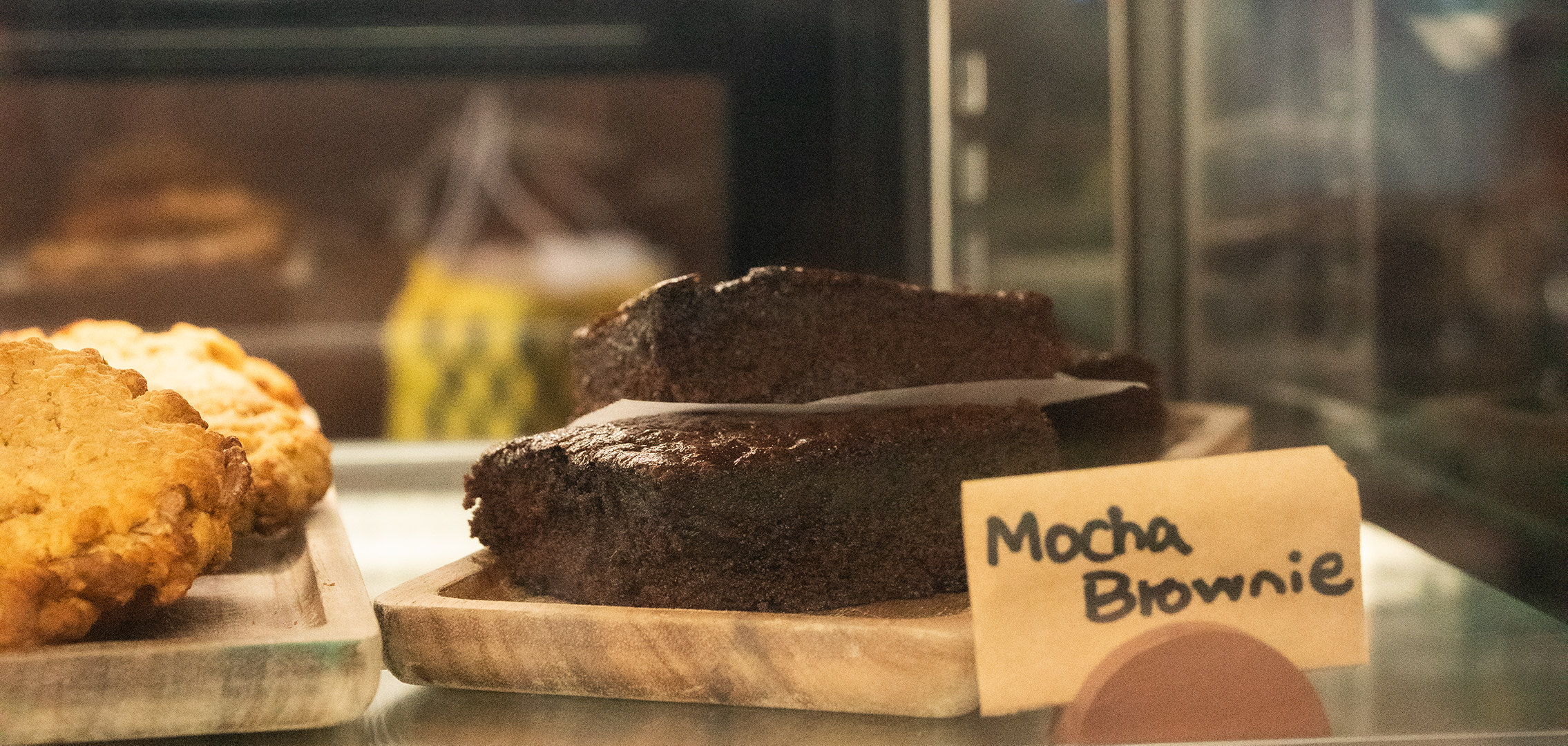 Mocha brownie sliced and ready on a wooden board, moody afternoon light.
