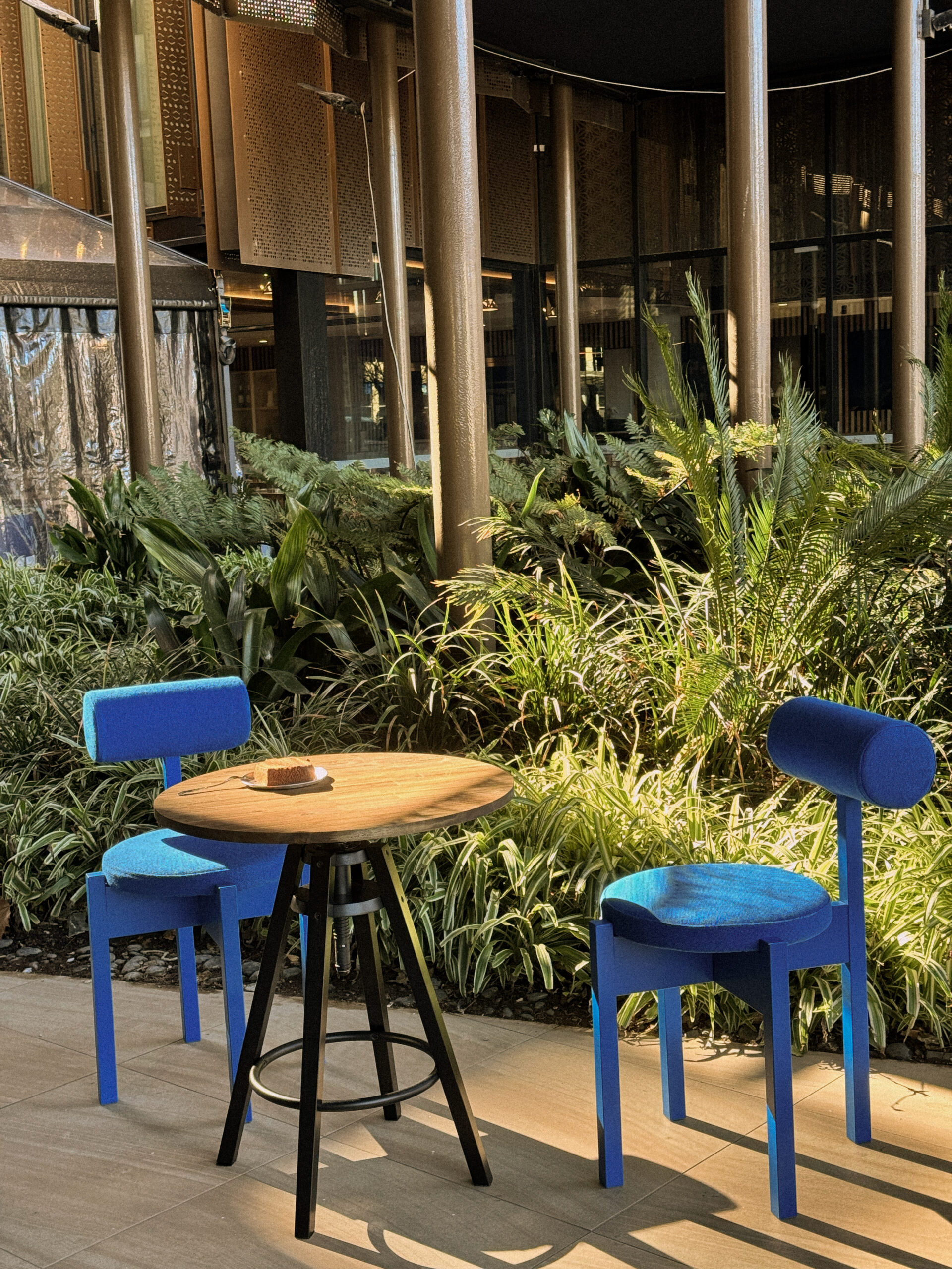 The outdoor seating area, framed by greenery and timber beams overhead.