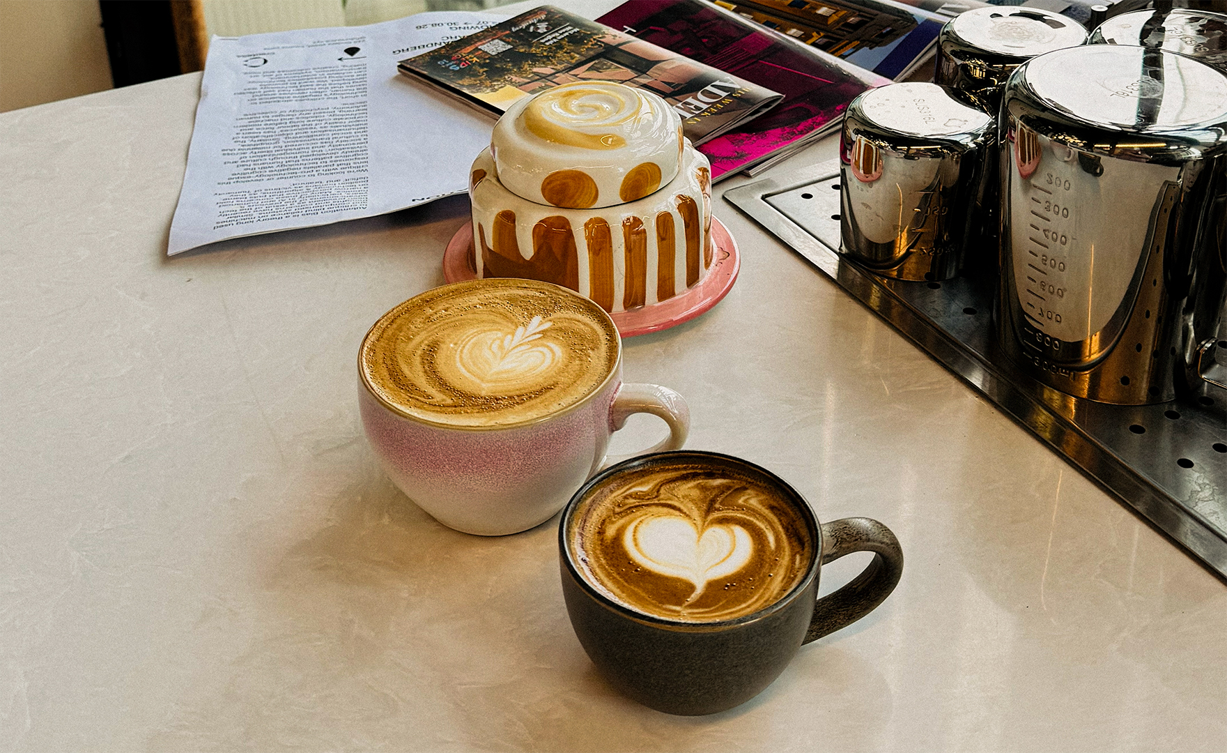 Two lattes with careful art, resting on the bench beside old photographs and notes.